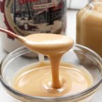 Soft maple cream oozing off a spoon into a small bowl with more maple cream.