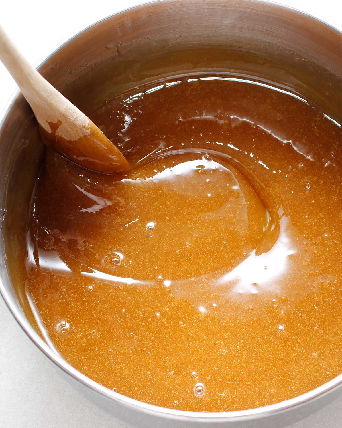 Stirring boiled maple syrup in a pot with wooden spoon.