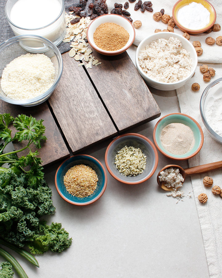 Grain-free ingredients in small bowls including some fresh greens.