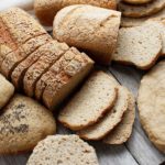 A display of gluten-free vegan bread (loaves, rolls, pizza crust) all prepared with one yeasted dough.