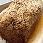 A freshly baked gluten-free vegan loaf of bread cooling on a wire rack.