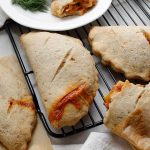 Gluten-free vegan sourdough calzones cooling on a wire rack.