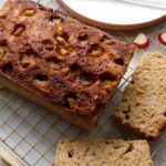 Sliced loaf of gluten-free rhubarb bread on a wire rack.