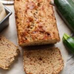 Sliced loaf of freshly baked zucchini bread with zucchini in the side