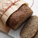Gorgeous low-carb gluten-free vegan bread wrapped in parchment paper, tied with a red ribbon.
